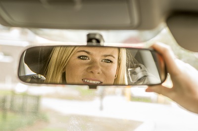 Young girl looking in rear view mirror.