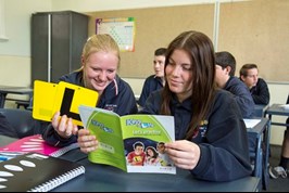 Two female students holding L plates and reading Keys4Life booklet