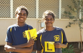 Two Aboriginal male students holding L platess